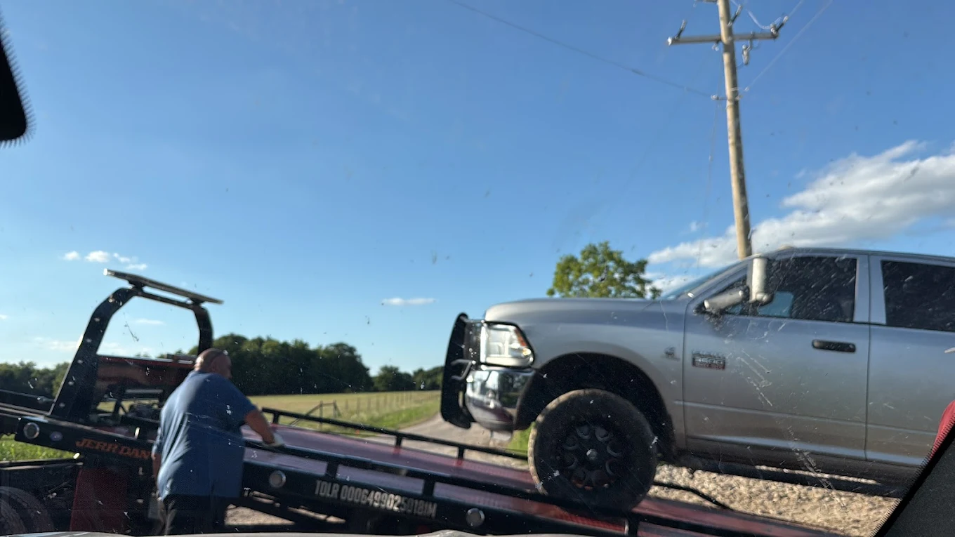 Flatbed tow truck picking up a junk car in Texas